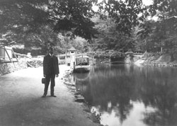 Man standing along Meander Creek with boats in background