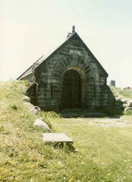Photo of a crypt damaged by the 1985 tornado. Damage is confined to upper wall next to roof on the left side.
