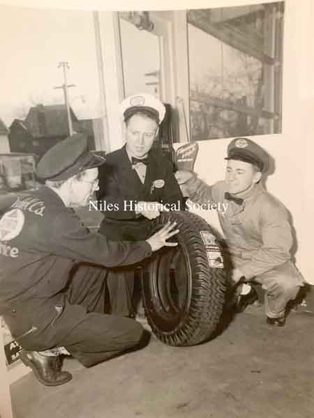 Three men inspecting a car tire.