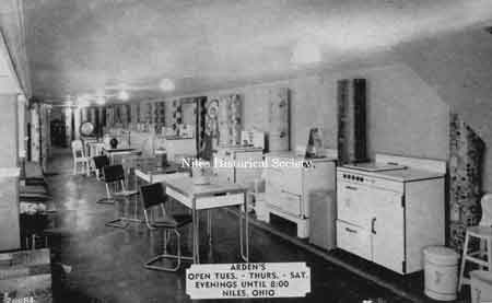 Postcard advertisement displaying metal tube kitchen tables and chairs, rolls of linoleum flooring and stoves.