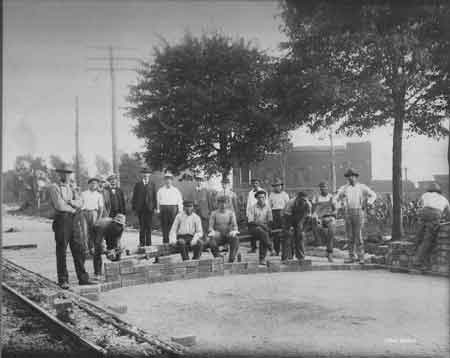 Workers laying the paver bricks on North Main Street with the DeForest guard house in the background.