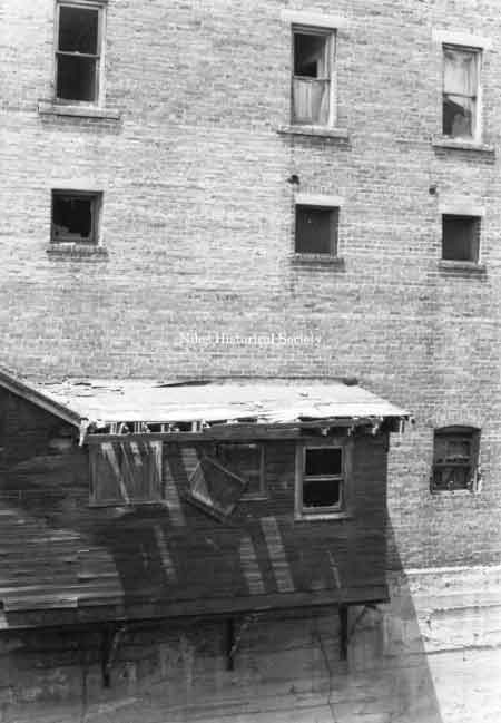 Photo taken of rear facade of building overhanging Mosquito Creek showing marked deterioration.