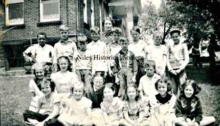 Group of children and teacher posing for a photograph near the front of Monroe School.