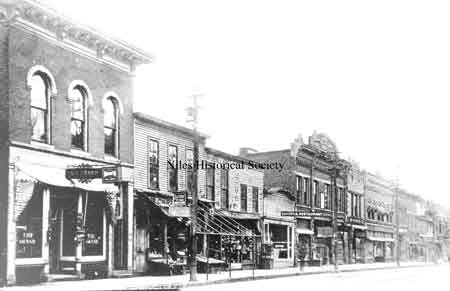 This picture was taken about 1905. "The Grand" dominates the block. Carmella's had opened their Ice Cream Parlor next to it. Later, T. W. Morral's Clothing Store and the Bakery & Restaurant would be replaced with brick buildings. The Armstrong-Morral Building would become the Ideal Department Store and the Wagstaff Building, Ragazzo's Men's Shop. The Crandon Building built in 1904 became Hoffman's Store the following year.
