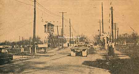 View of North Main Street grade crossing with gates and watch tower guarding the railroad crossover at this location as it looked in 1953, prior to the Grade Elimination Project.