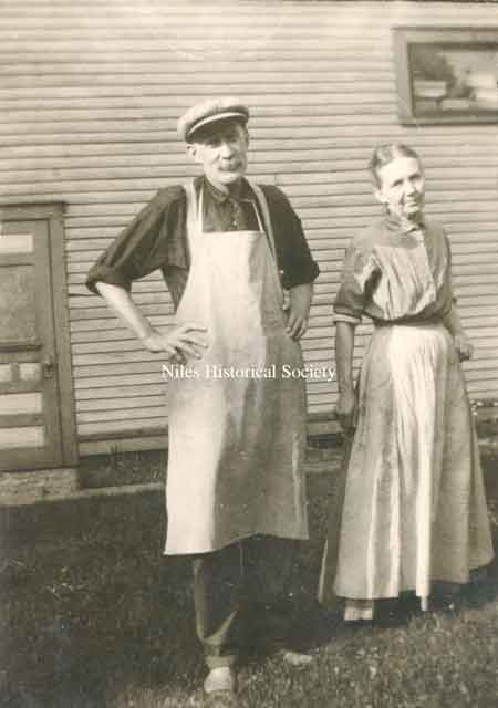 Henry and Elizabeth (Stein) Rider standing on the side of H.F. Rider Grocery Store at 142 Vienna Avenue.