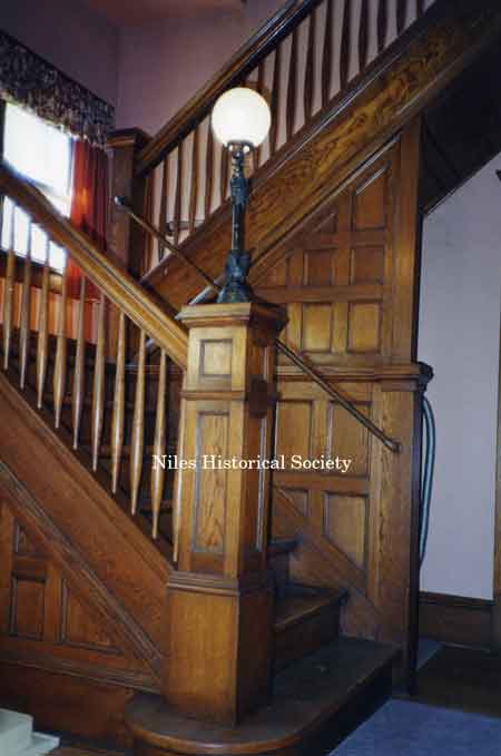 The staircase has a landing with a window providing natural light to flood the stairwell and note the craftsman lamp on the first floor pedestal.