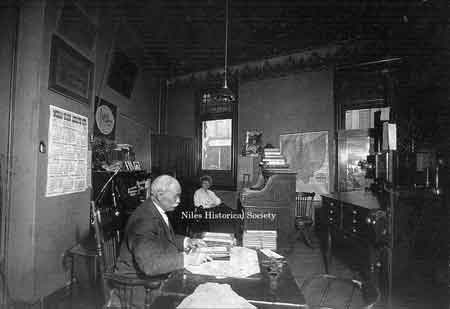 February 1917, Allie Taylor in background with George Taylor, at Home Federal Savings Bank located in the Hartzell Building, built 1889, corner of Main and State Streets, Niles, Ohio.