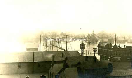 A postcard photo of the 1913 flood as seen from the rooftops of Main Street looking south from town. The Southside Presbyterian Church is visible in the far right.