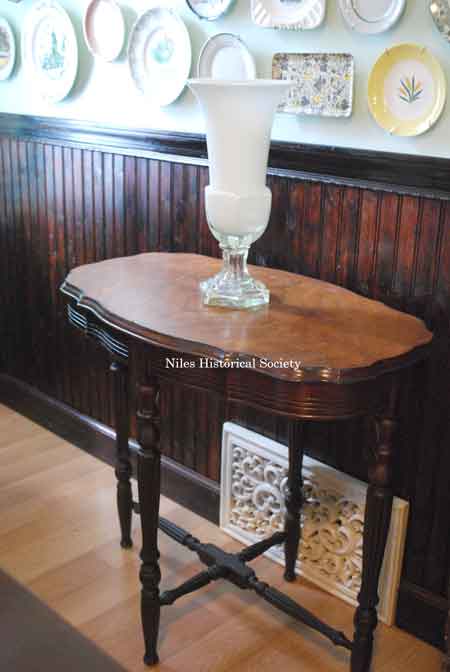 refinished wooden floors, ornate floor register, wainscoting, plate display, and typical trestle wooden table.